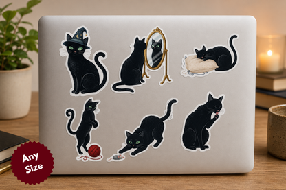 Laptop with black cat stickers on a wooden surface with a plant and candle in the background
