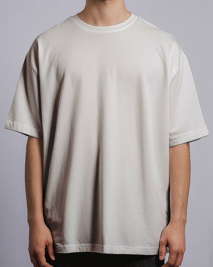 Person wearing a plain beige t-shirt on a gray background